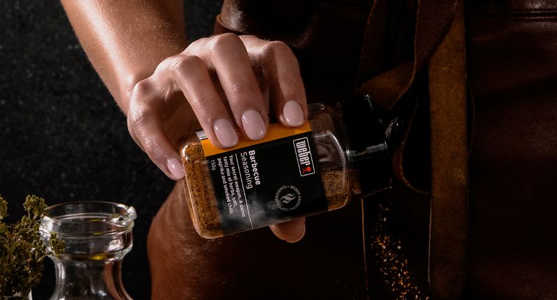 barbeque seasoning spices being sprinkled from branded packaging